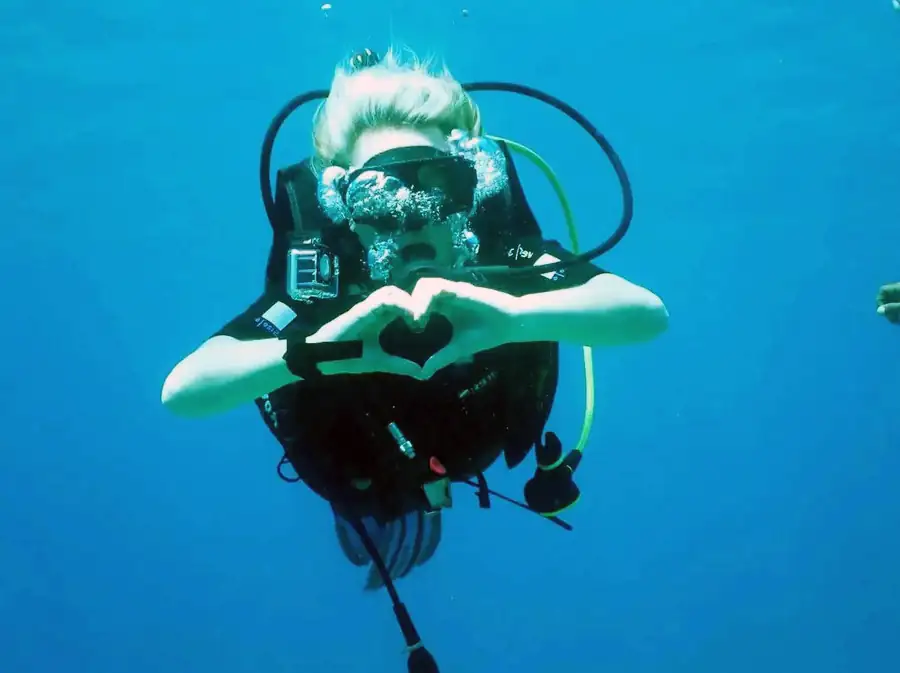 Diver making a heart shape with hands underwater Noura Resort